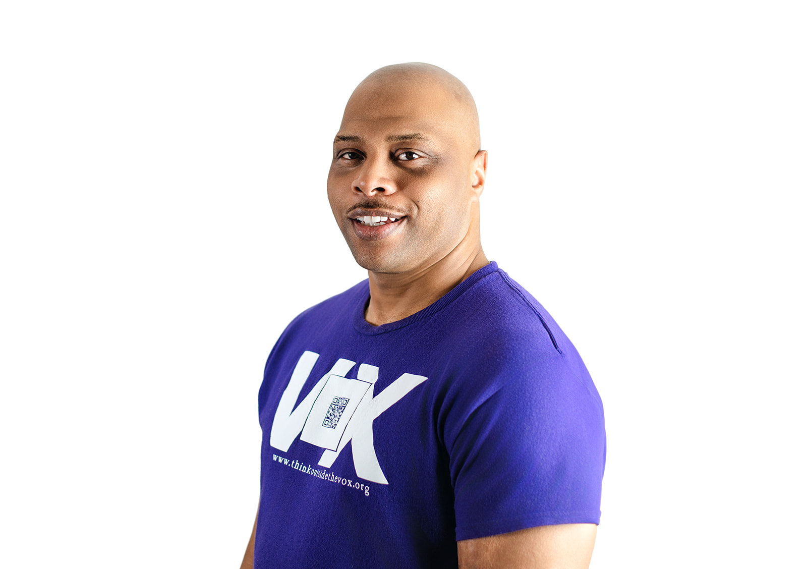 a tall, broad-shouldered African American with a freshly shaven bald head and sharp mustache curled over thick lips permanently curled in an excitable smile wearing a purple Vox shirt